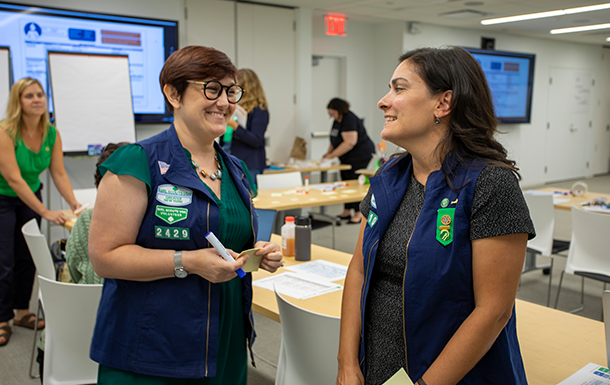 adult woman girl scout volunteer wearing vest outdoors smiling hiking