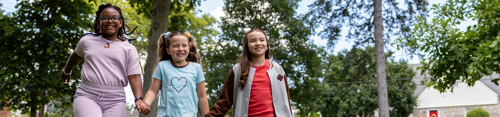  three young girl scouts with their arms wrapped around one another and smiling at the camera 